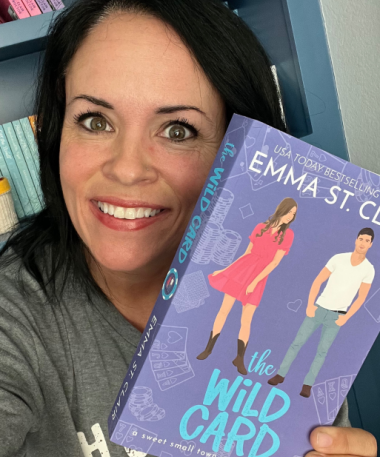 Author Emma St. Clair holding up a copy of The Wild Card